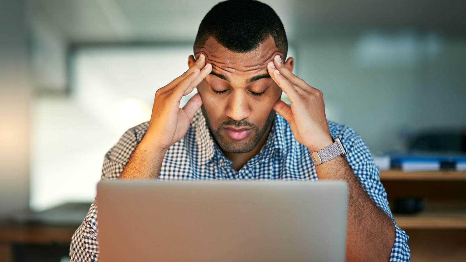 Man stressed rubbing forehead while working